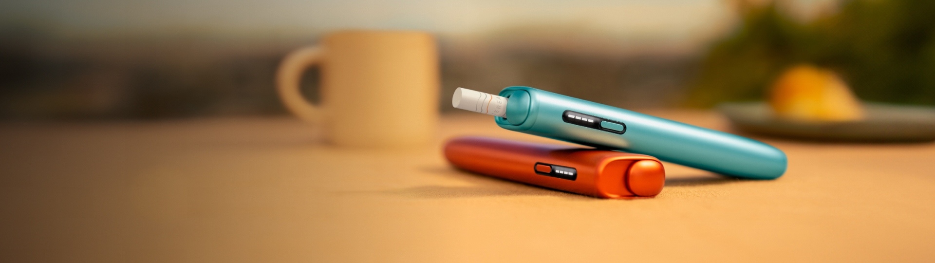 An IQOS device held by one person and a smartphone held by another person.